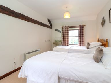 A bedroom with two single beds and a window with checked curtains at Addyfield Farmhouse in Cartmel Fell near Bowland Bridge