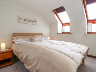 A bedroom with a bed and bedside table under two skylight windows at Addyfield Farmhouse in Cartmel Fell near Bowland Bridge