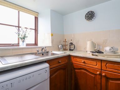 A kitchen corner with a sink cups kettle and clock at Addyfield Farmhouse in Cartmel Fell near Bowland Bridge