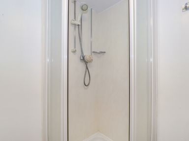 A shower stall with a mounted showerhead and a small metal shelf at Addyfield Farmhouse in Cartmel Fell near Bowland Bridge