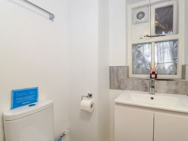 A bathroom with a toilet sink a window and a toilet paper holder at Addyfield Farmhouse in Cartmel Fell near Bowland Bridge