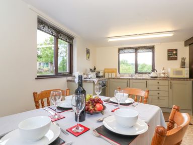 A kitchen with a dining table set with bowls wine glasses and fruit bowl at Addylea Cottage in Cartmel Fell near Windermere