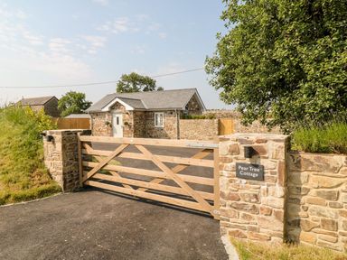 A stone cottage with a wooden gate and stone walls at Pear Tree Cottage in St Mellion near St Dominick