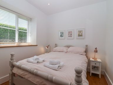 A bedroom with a bed with striped bedding two bedside tables with lamps and three framed pictures above the bed at Old Orchard Barn St Mellion near St Dominick