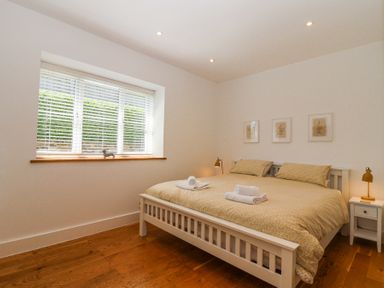 A bedroom with a large bed and bedside tables with lamps at Old Orchard Barn St Mellion near St Dominick