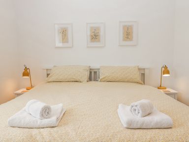 A bedroom with a double bed two bedside tables with lamps and three framed pictures above the bed at Old Orchard Barn St Mellion near St Dominick