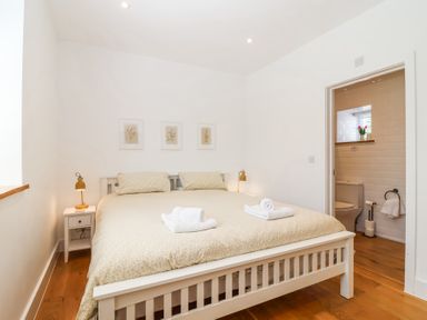 A bedroom with a double bed two bedside tables and a view of a bathroom at Old Orchard Barn in St Mellion near St Dominick