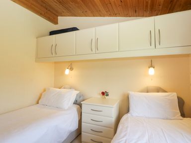 A bedroom with two single beds and a white nightstand with drawers at Lodge 16 in Whitsand Bay near Millbrook
