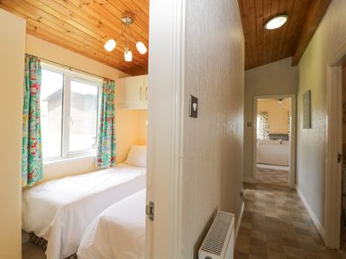 A view down a hallway with a bedroom having two single beds and colorful curtains at Lodge 16 Whitsand Bay near Millbrook