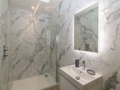 A bathroom with a walk-in shower and a sink with a mirror at Y Felin in Caernarfon