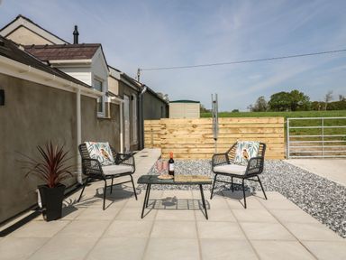 An outdoor patio with two chairs and a table with drinks and snacks at Y Felin in Caernarfon