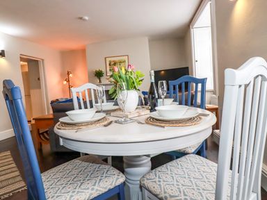 A dining table set with bowls glasses and flowers with chairs in a living room at Carew House Cottage in St Day