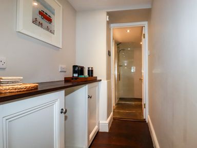 A hallway with cabinets and a coffee station leading to a bathroom with a shower at Carew House Cottage in St Day
