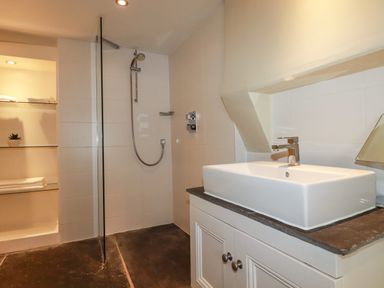 A bathroom with a walk-in shower on the left and a rectangular sink on a vanity unit at Carew House Cottage in St Day