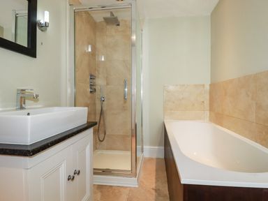 A bathroom with a white sink vanity unit a glass shower cubicle and a bathtub at Carew House Cottage in St Day