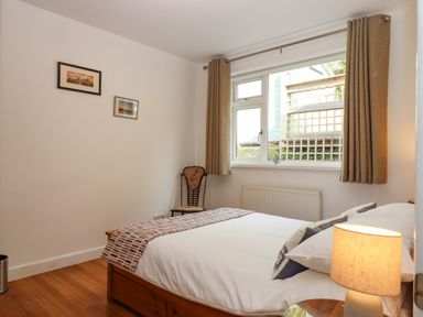 A bedroom with a bed chair bedside table and lamp at Sandy Toes in Paignton