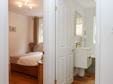A bedroom with a bed and chair next to a bathroom with a sink and mirror at Sandy Toes in Paignton