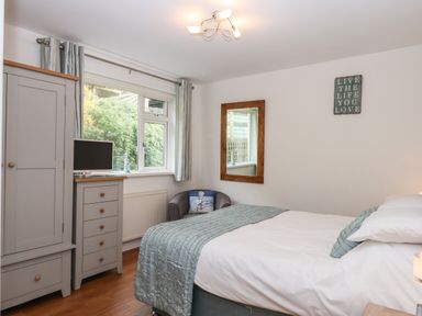 A bedroom with a bed a wardrobe a chest of drawers and a chair at Sandy Toes in Paignton