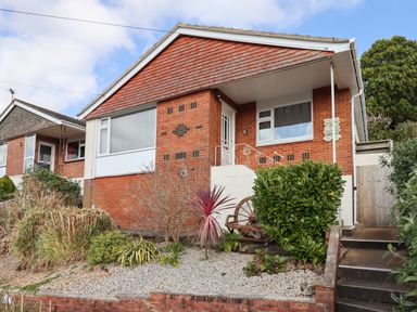 A brick house with a front garden and steps leading to the entrance at Sandy Toes in Paignton