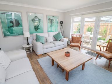 A living room with sofas chairs a wooden coffee table and framed artwork on the wall at Turnstone in Beadnell