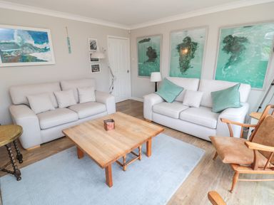 A living room with two beige sofas a wooden coffee table and art on walls at Turnstone in Beadnell