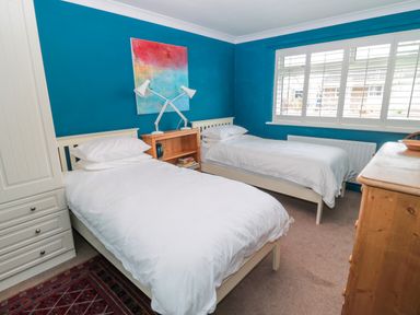 A bedroom with two single beds a wooden dresser and a wooden bedside table with lamps at Turnstone in Beadnell