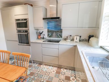 A kitchen with patterned tile floor wooden chairs oven stovetop and countertop appliances at Turnstone in Beadnell