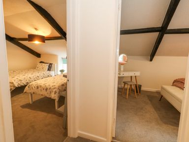 Two adjoining rooms one with two single beds and the other with a dressing table and sofa at Half Pint Cottage Beaminster