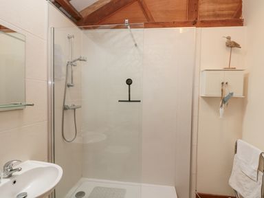 A bathroom with a shower area glass panel sink mirror cabinet and towel rack at Fulmar Cottage in Flamborough