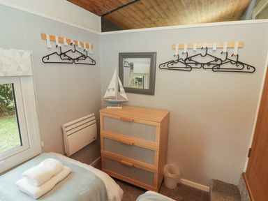 A bedroom corner with a wooden chest of drawers a mirror and clothes hangers on the wall at The Bird House in Cenarth