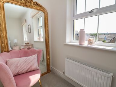 A living room with a pink chair and mirror at Seashell Sands in Appledore