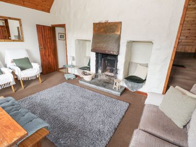 A living room with a fireplace two armchairs a sofa and a gray rug at Bofin in Oughterard County Galway