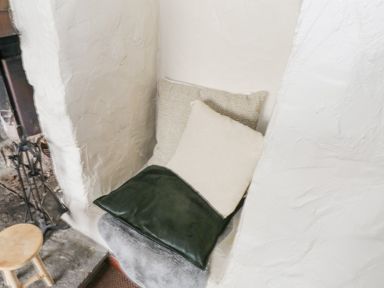 A small seating nook with cushions next to a fireplace with fire tools at Bofin in Oughterard County Galway