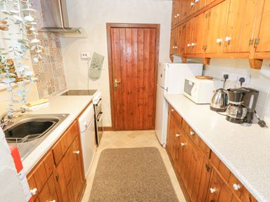 A kitchen with wooden cabinets a refrigerator microwave coffee maker kettle stove and sink at Bofin in Oughterard County Galway
