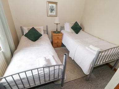 A bedroom with two single metal frame beds a wooden nightstand with a lamp between the beds and a framed picture on the wall at Bofin in Oughterard County Galway