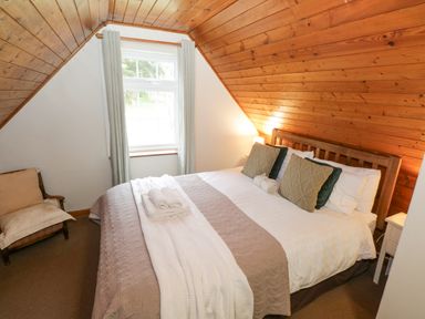 A bedroom with a wooden bed and pillows under a sloped wooden ceiling at Bofin in Oughterard County Galway