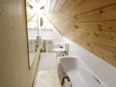 A bathroom with a bathtub towel toilet sink mirror and wooden ceiling at Bofin in Oughterard County Galway