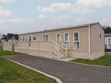 A beige mobile home with a small staircase and a railing on the side at Whispering Willows in Cayton Bay