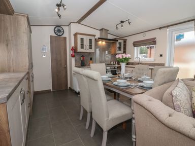 A kitchen and dining area with a dining table set for six and a sofa at Whispering Willows in Cayton Bay