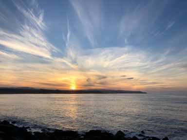A sunset over the ocean with clouds at Whispering Willows in Cayton Bay