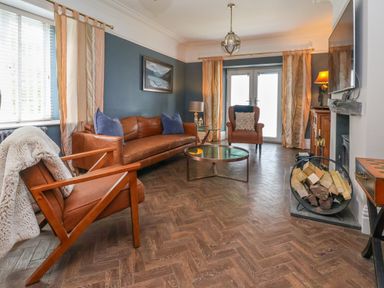 A living room with leather chairs wood log holder and a round coffee table at The Manor House Skerry Vore Bryn Pydew near Llandudno Junction