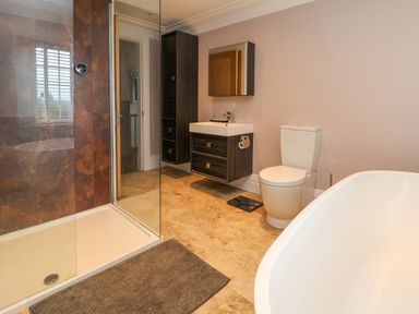 A bathroom with a shower, floating sink vanity, toilet, and bathtub at The Manor House Skerry Vore Bryn Pydew near Llandudno Junction