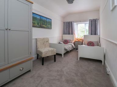 A bedroom with two single beds a nightstand a wardrobe and a chair at The Manor House Skerry Vore Bryn Pydew near Llandudno Junction