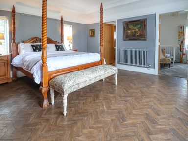 A bedroom with a four-poster bed bench two nightstands with lamps and artwork on the walls at The Manor House Skerry Vore Bryn Pydew near Llandudno Junction