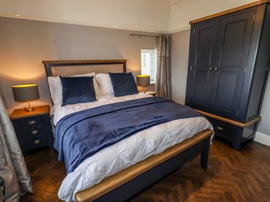 A bedroom with a bed two nightstands with lamps and a wardrobe at The Manor House Skerry Vore Bryn Pydew near Llandudno Junction