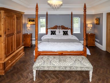 A bedroom with a four-poster bed nightstands and a wooden wardrobe at The Manor House Skerry Vore Bryn Pydew near Llandudno Junction