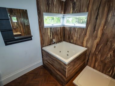 A bathroom with a corner bathtub shower tray and wall mirror at The Manor House Skerry Vore Bryn Pydew near Llandudno Junction