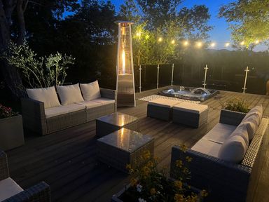An outdoor deck with sofas tables a heater string lights and a hot tub at The Manor House Skerry Vore Bryn Pydew near Llandudno Junction