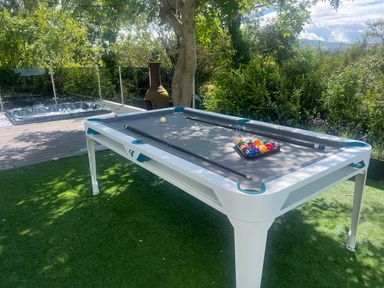 An outdoor area with a pool table on artificial grass and a hot tub on a wooden deck surrounded by trees at The Manor House Skerry Vore in Bryn Pydew near Llandudno Junction