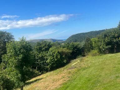 A landscape with trees a grassy hill and hills in the background at The Manor House Skerry Vore Bryn Pydew near Llandudno Junction